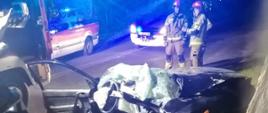 Widoczne miejsce zdarzenia uszkodzony pojazd oraz służby działające na miejscu- straż pożarna, Pogotowie Ratunkowe, Policja
