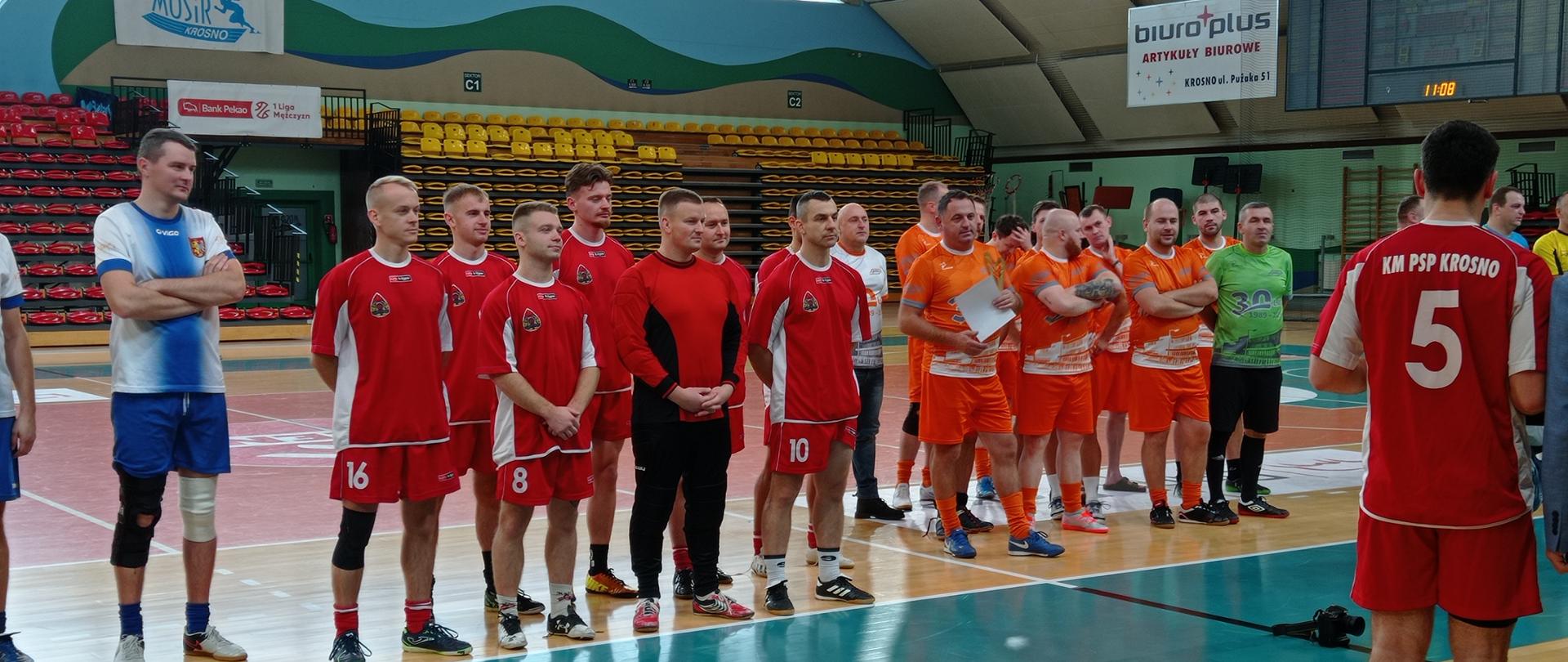 Na zdjęciu widoczna jest reprezentacja KM PSP Krosno w futsalu oraz reprezentacja innego zakładu z powiatu Krośnieńskiego. Zawodnicy brali udział w turnieju o Puchar Dyrektora MOSiR Krosno. Zawodnicy stoją w strojach sportowych na hali sportowej