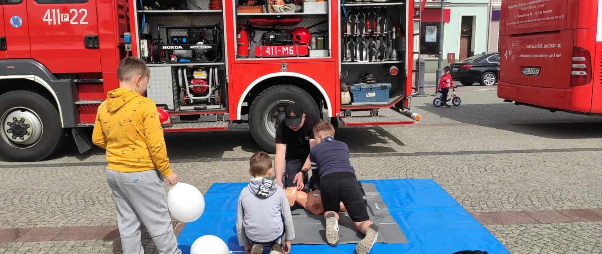 Strażak uczy dzieci jak udzielać pierwszej pomocy.