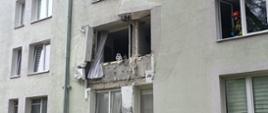 Na zdjęciu widoczny jest budynek w którym doszło do eksplozji, wyrwane jest okno, które leży na trawniku.