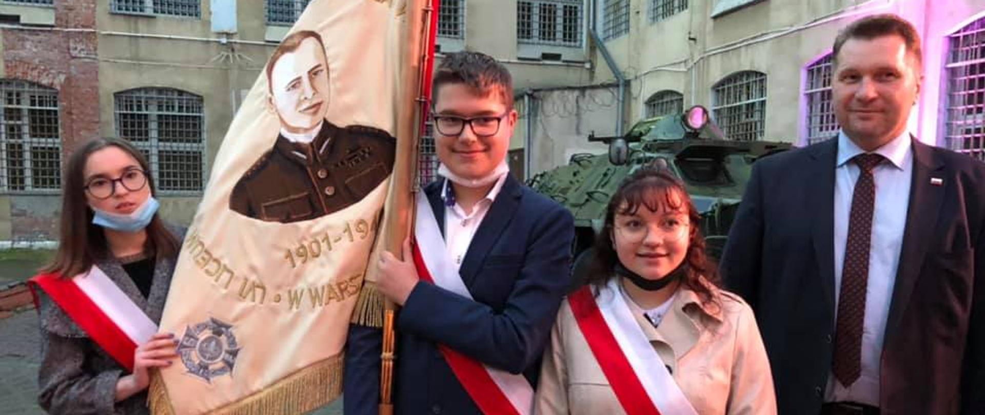 Minister Edukacji i Nauki wraz z dziećmi, które trzymają sztandar