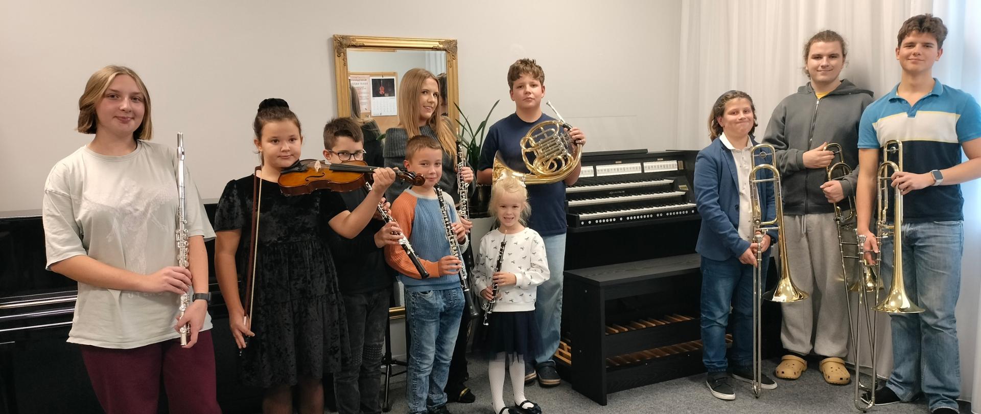 Zdjęcie grupowe uczniów z nowymi instrumentami na tle organów.