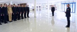 Po prawej Zastępca Komendanta Centralnej Szkoły PSP przemawiający podczas uroczystości zakończenia roku szkolnego, po lewej stojąca w rzędach kompania kadetów XXVII turnusu dziennego studium aspirantów PSP, w głębi na środku stojący na baczność dowódca uroczystości