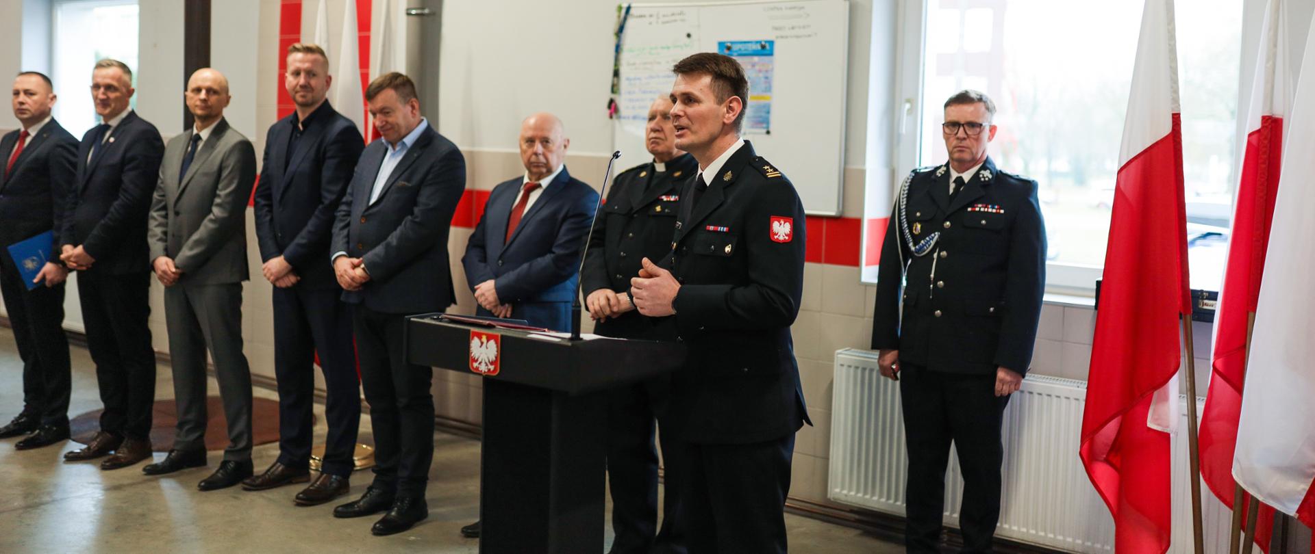 Zastępca Zachodniopomorskiego Komendanta Wojewódzkiego podczas okolicznościowego przemówienia. W tle widoczni są goście zaproszeni na uroczystość przekazania samochodu dla OSP Orzechowo.