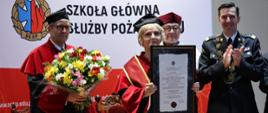  Doktor Honoris Causa Szkoły Głównej Służby Pożarniczej prezentująca pamiątkowy dyplom