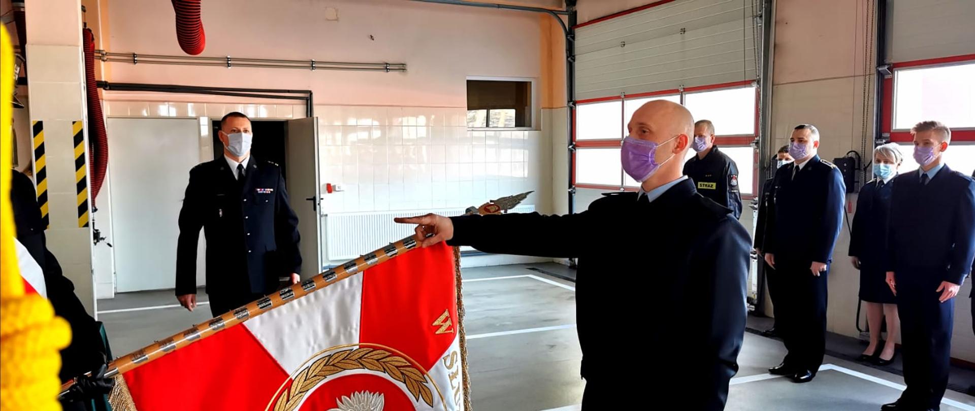 do opuszczonego sztandaru z wyciągniętą prawą ręką ślubuje funkcjonariusz. W tle stoją koledzy z KP PSP Sztum