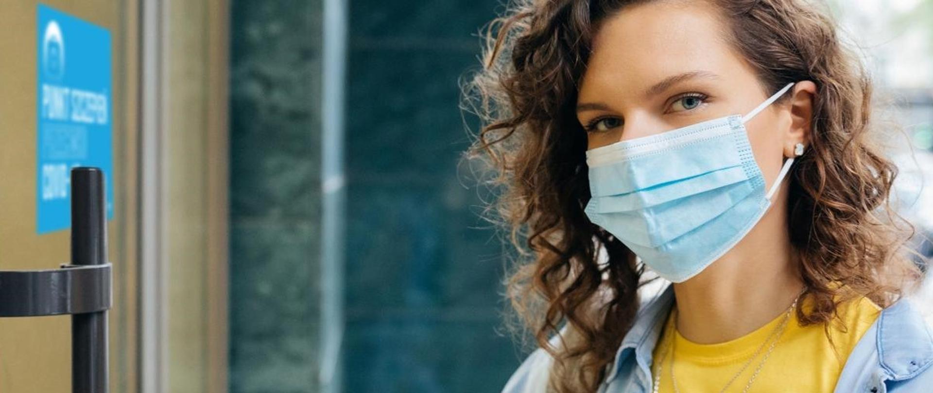Zdjęcie przedstawiające młodą kobietę wchodzącą do punktu szczepień