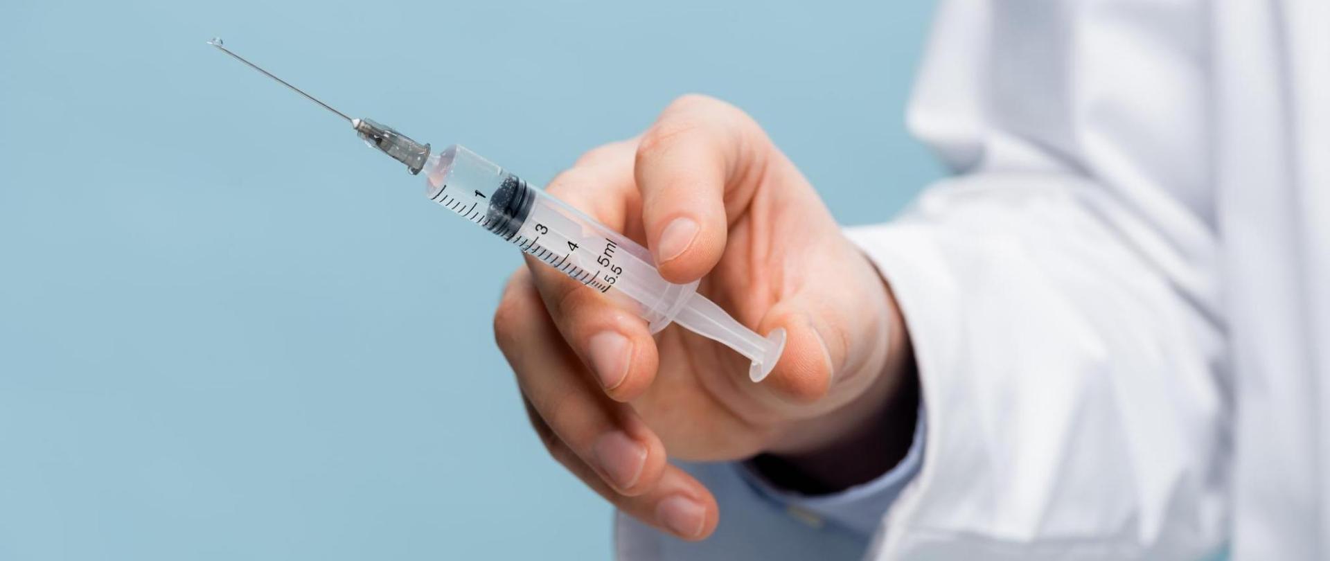 Na zdjęciu jest medyk, który w ręku trzyma strzykawkę.