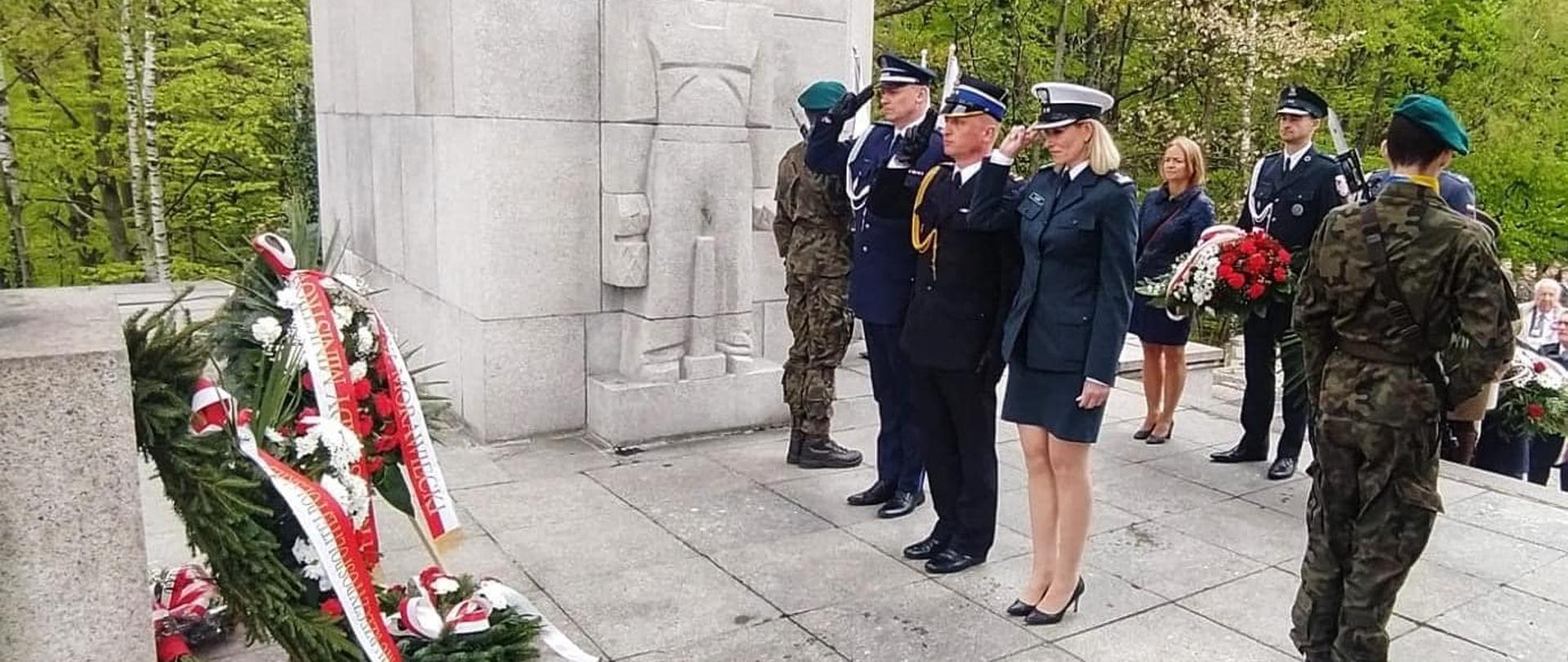 Na zdjęciu znajdują się delegacje ustawione do złożenia wiązanek pod Pomnik Czynu Powstańczego, w tle widać drzewa oraz fragment pomnika