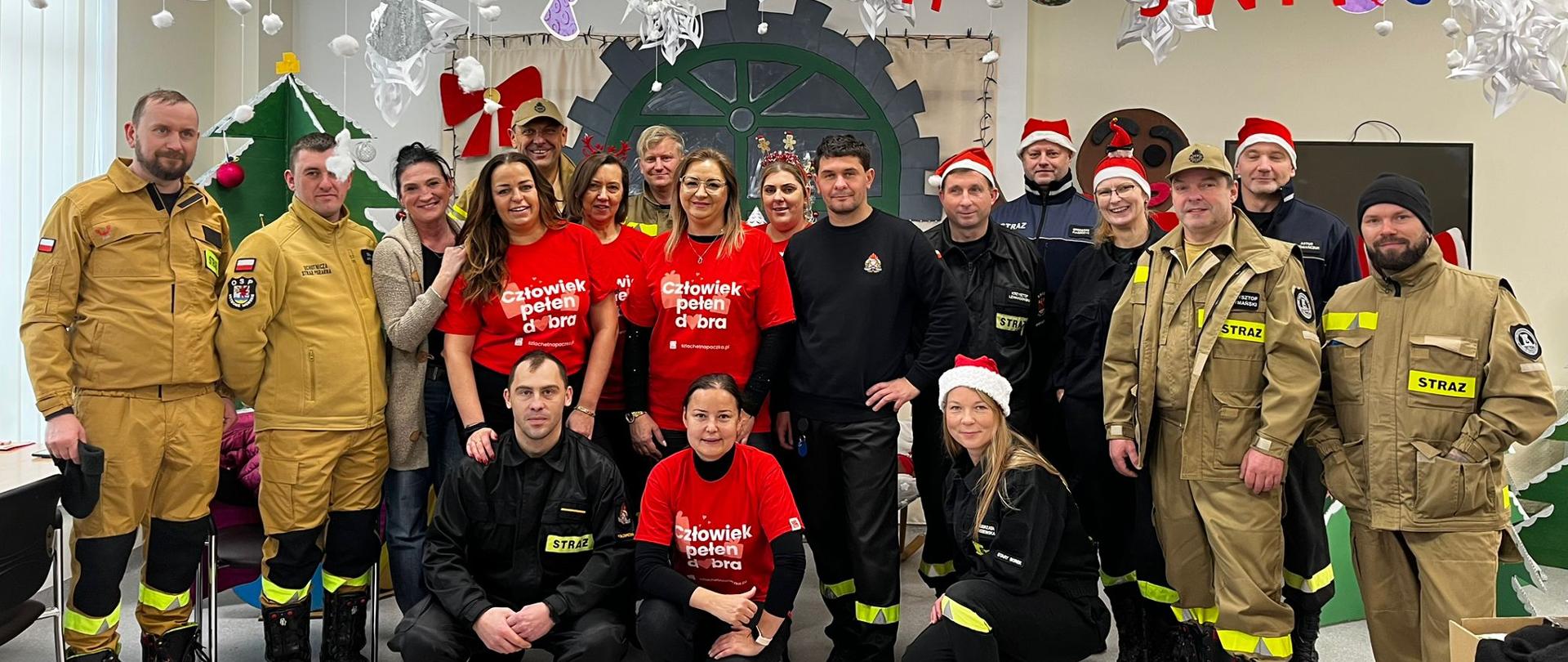 Grupa strażaków i wolontariuszy pozuje do zdjęcia grupowego w ramach "Szlachetnej Paczki"