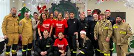Grupa strażaków i wolontariuszy pozuje do zdjęcia grupowego w ramach "Szlachetnej Paczki"