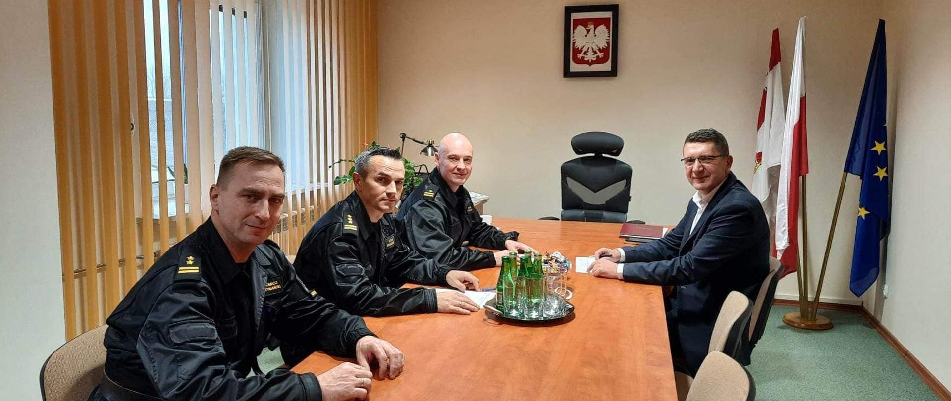 Zdjęcie obrazuje komendanta wojewódzkiego Państwowej Straży Pożarnej st. bryg. Artur Brachowicz w asyście komendanta powiatowego PSP w Jędrzejowie mł. bryg. Mariusza Stolarczyka oraz zastępcy bryg. Tomasza Szymańskiego, którzy siedzą przy stole w urzędzie gminy. Na zdjęciu widoczny także wójt gminy Sobków Pan Tomasz Chaja.