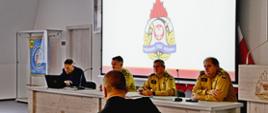 Kierownictwo Komendy Wojewódzkiej PSP w Gdańsku, przedstawiciel Komendy Głównej Państwowej Straży Pożarnej rozpoczynają spotkanie zespołu. Przed strażakami siedzi dyrektor Morskiej Służby Poszukiwania i Ratownictwa.
