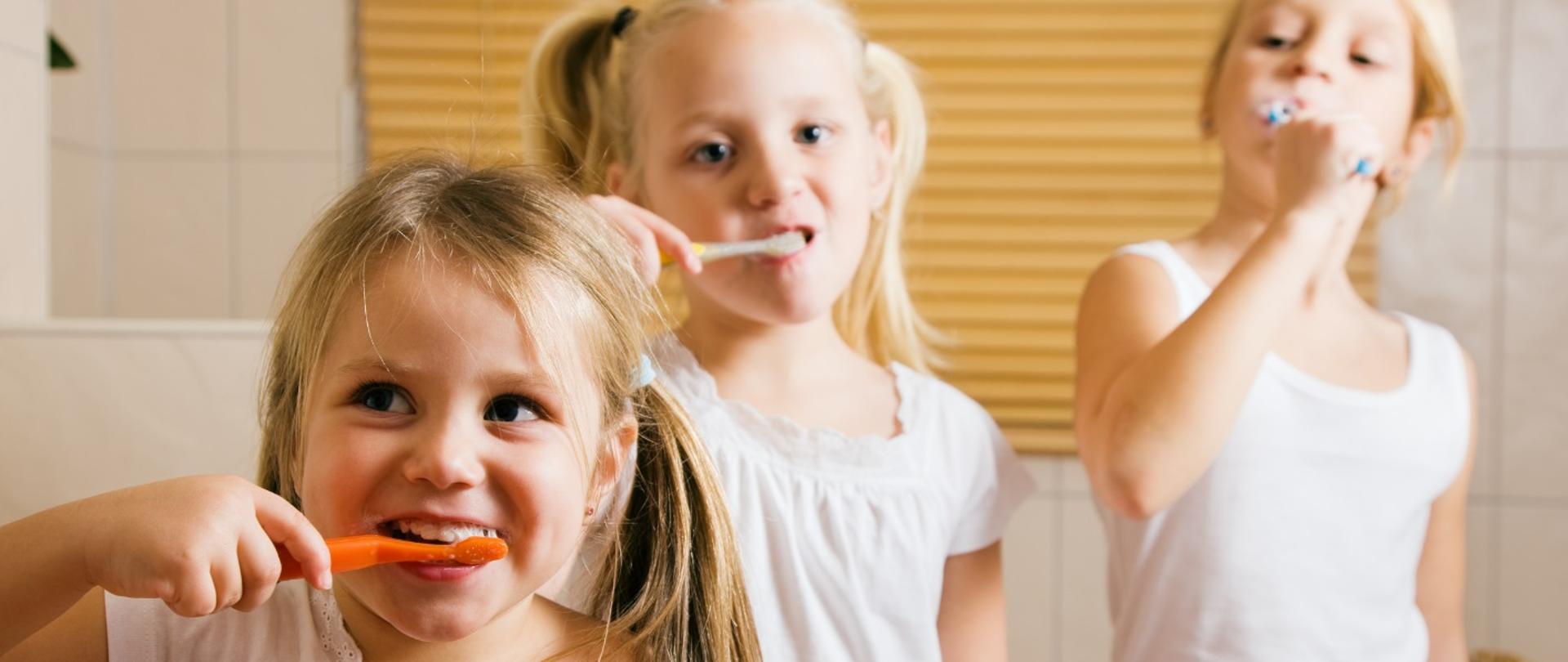 zdjęcie trójki dzieci myjących zęby