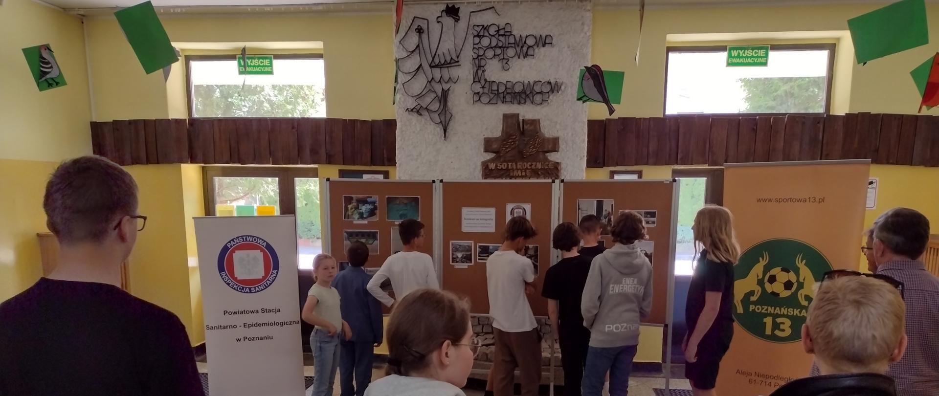 w holu szkoły na stelażach wyeksponowano prace konkursowe, po bokach stoją banery PSSE
