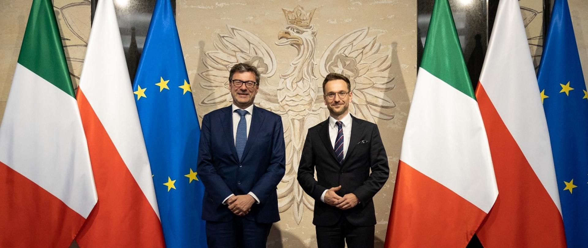 Minister rozwoju i technologii Waldemar Buda z ministrem rozwoju gospodarczego Republiki Włoskiej Giancarlo Giorgettim, ministrowie stoją obok flag Polski, Włoch i Unii Europejskiej