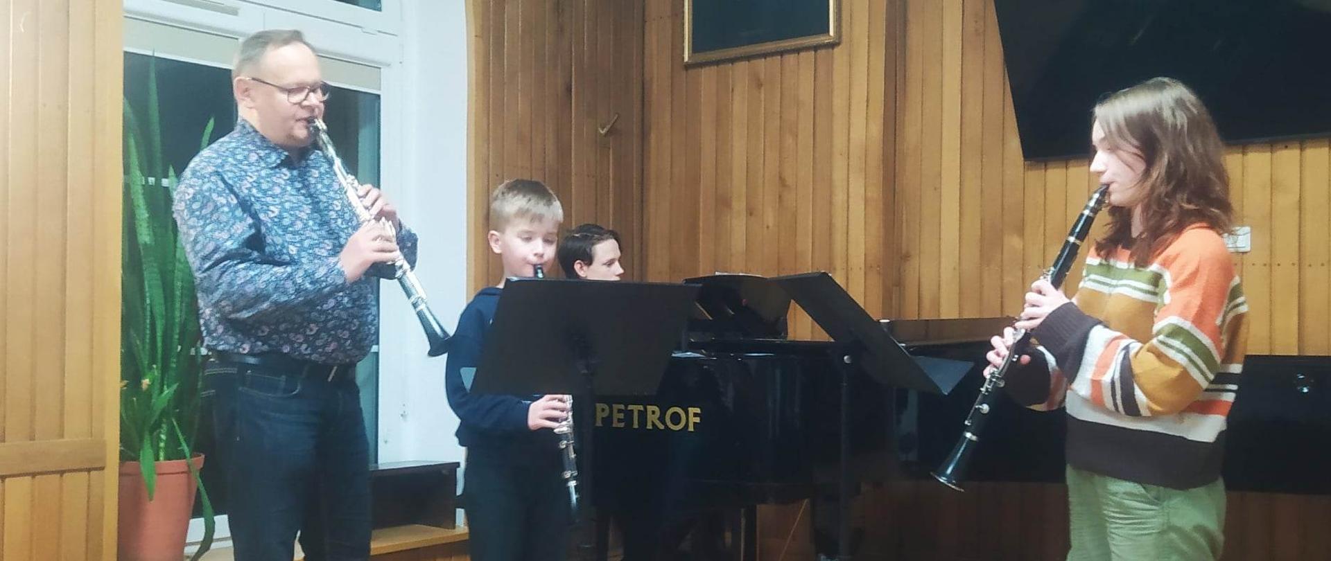 Fotografia przedstawia nauczyciela oraz ucznia grających w klasie na klarnetach