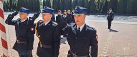 Strażacy salutują do flagi, która znajduje się na maszcie.