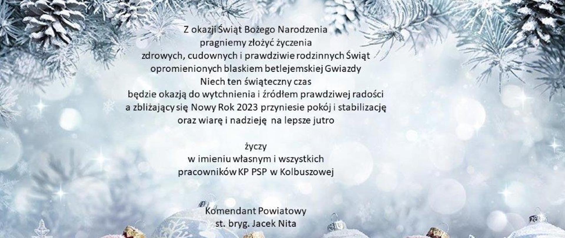 Na środku tekst z życzeniami z okazji świąt Bożego Narodzenia składane przez Komendanta Powiatowego st. bryg. Jacka Nitę. Życzenia na tle obrazka świątecznego: w górnej części oszronione choiny z szyszkami, w dolnej części zaszronione bąbki choinkowe.