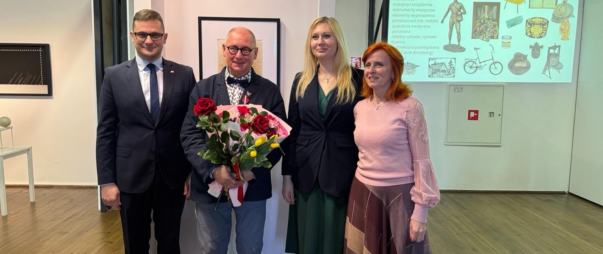 Zdjęcie grupowe podczas uroczystej ceremonii wręczenia Brązowego Medalu Gloria Artis zasłużonemu kulturze fotografowi Wojciechowi Woźniakowi w Galerii Sztuki Nowoczesnej MOB w Bydgoszczy