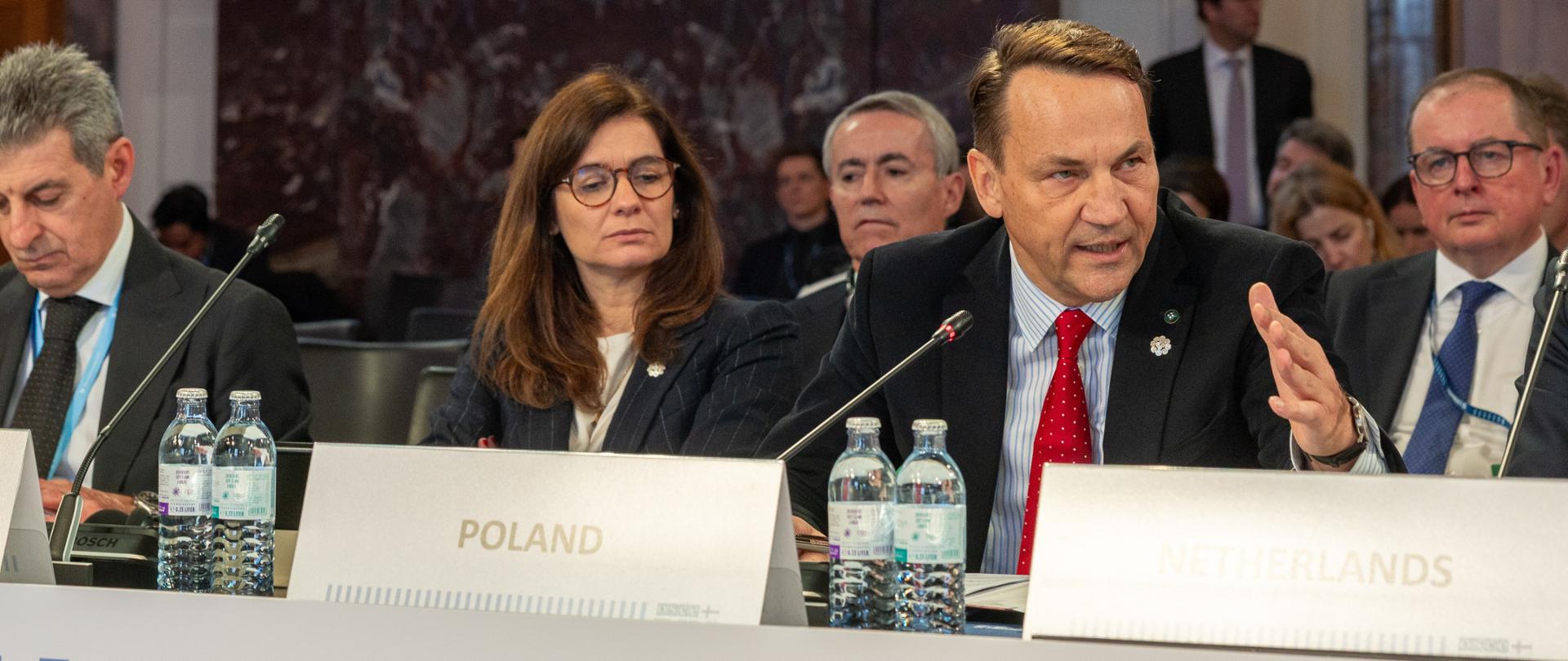The photo depicts Minister Radosław Sikorski delivering a statement at the 32nd OSCE Ministerial Council