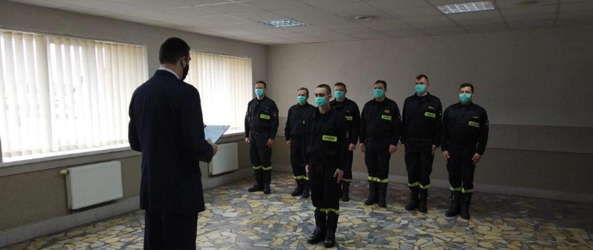 Zdjęcie przedstawia złożenie ślubowania przez nowo zatrudnionego funkcjonariusza w obecności Komendanta Powiatowego PSP w Oleśnicy. Ślubowanie odbywa się w świetlicy JRG w Sycowie.