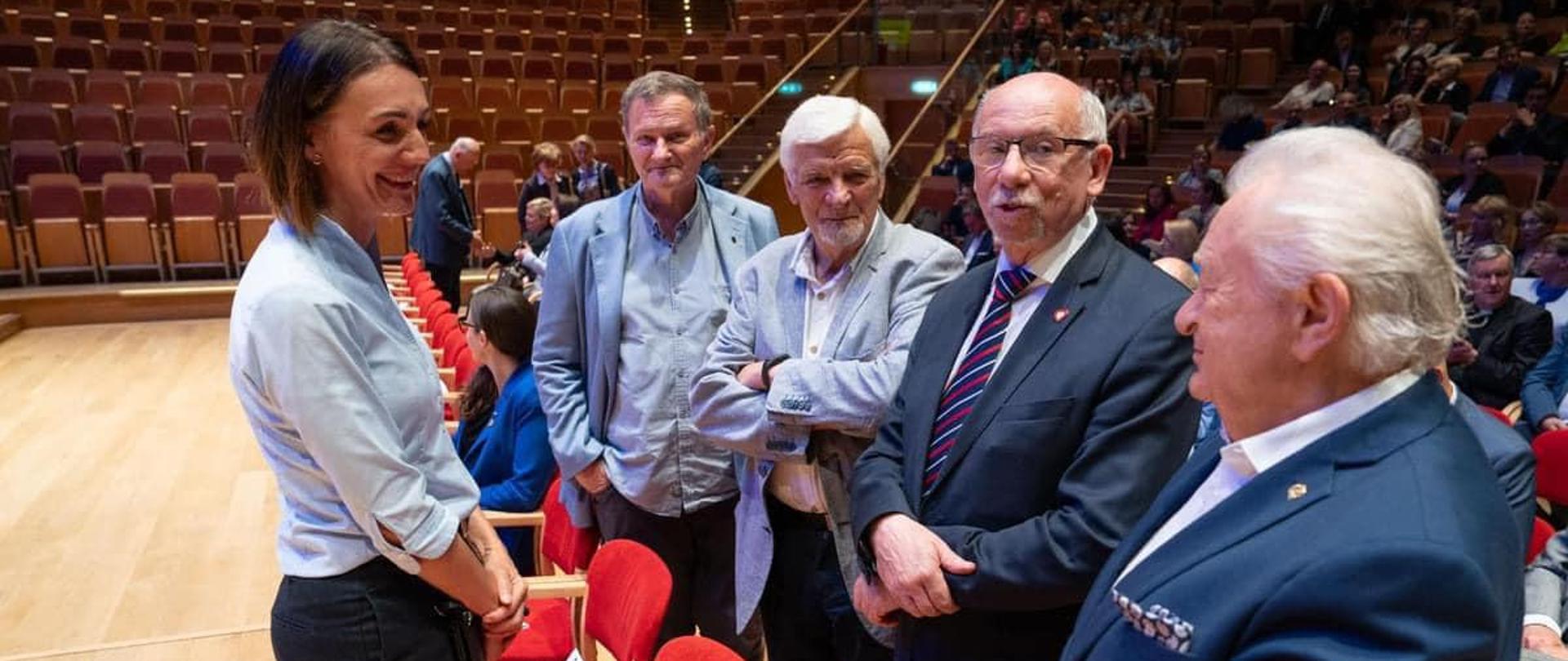 Grupa osób stoi w dużej sali i rozmawia, wśród nich kobieta - wojewoda pomorska