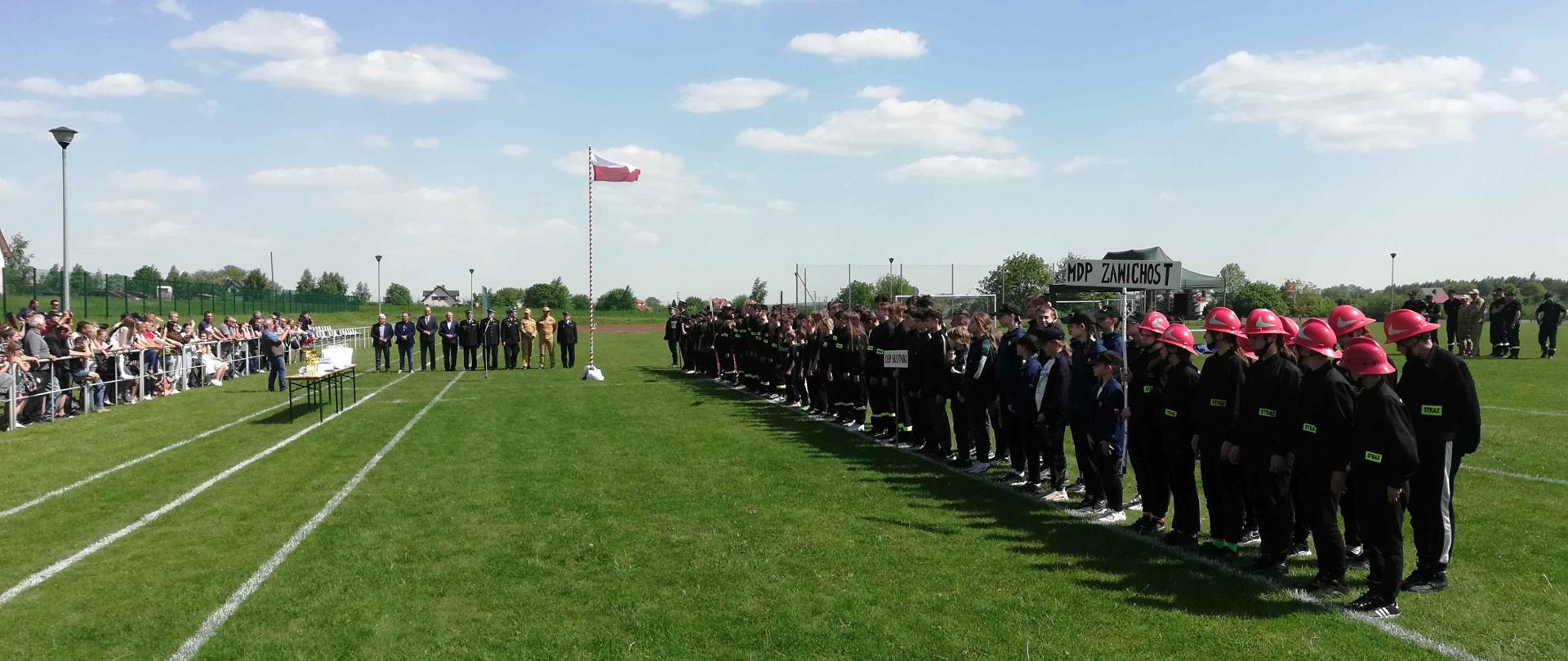 młodzież MDP stojąca w zbiórce na boisku sportowym przed zawodami.