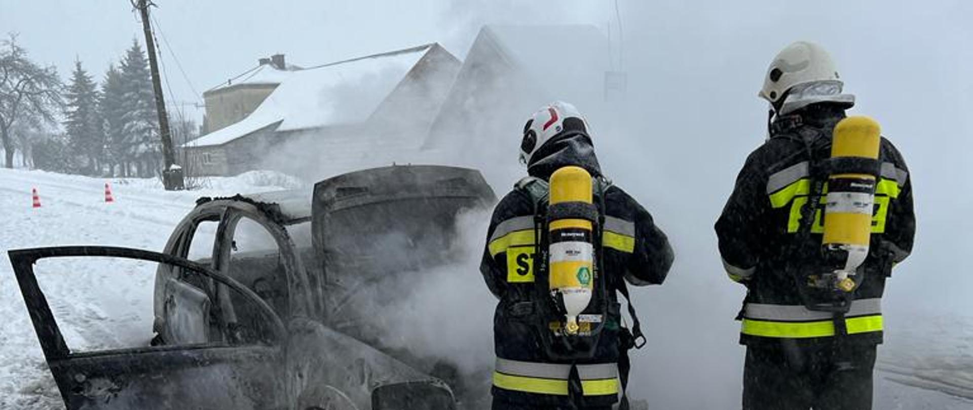 Strażacy gaszą pożar samochodu.