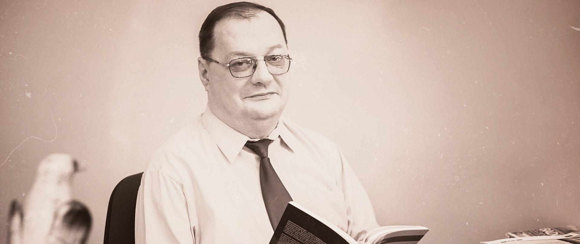 Mężczyzna w okularach, siedzący z książką w rękach