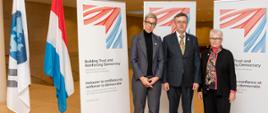 Uczestnicy sesji ministerialnej Komitetu Zarządzania Publicznego OECD, Luksemburg, 18 listopada 2022 r. - od lewej: minister sprawiedliwości Luksemburga Sam Tanson, szef służby cywilnej Dobrosław Dowiat-Urbański, zastępca sekretarza generalnego OECD Kerri-Ann Jones (stoją na tle plakatów z hasłem przewodnim spotkania, obok flagi Luksemburga i OECD)