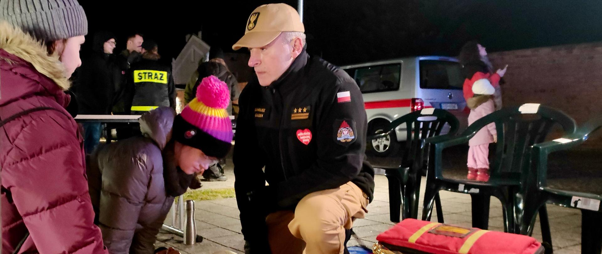 pod namiotem komendant powiatowy psp w brzezinach starszy brygadier dariusz Guzek pokazuje dzieciom jak poprawnie prowadzić resuscytację na manekinie