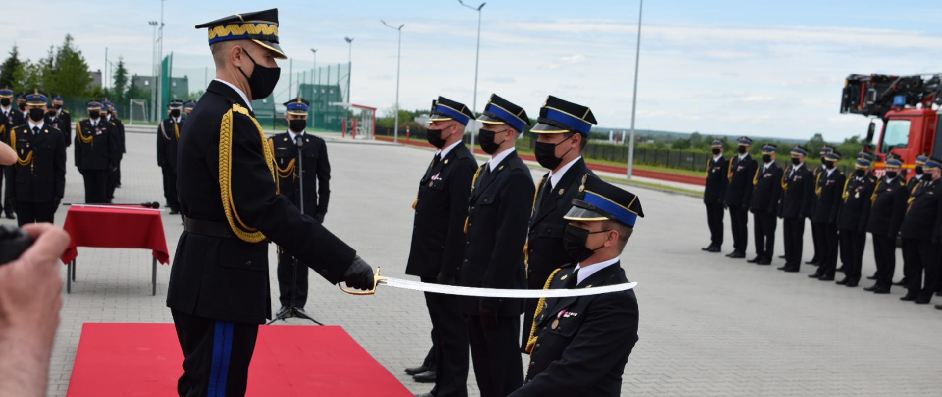 Komendant główny z szablą nadaje stopnie oficerskie. 