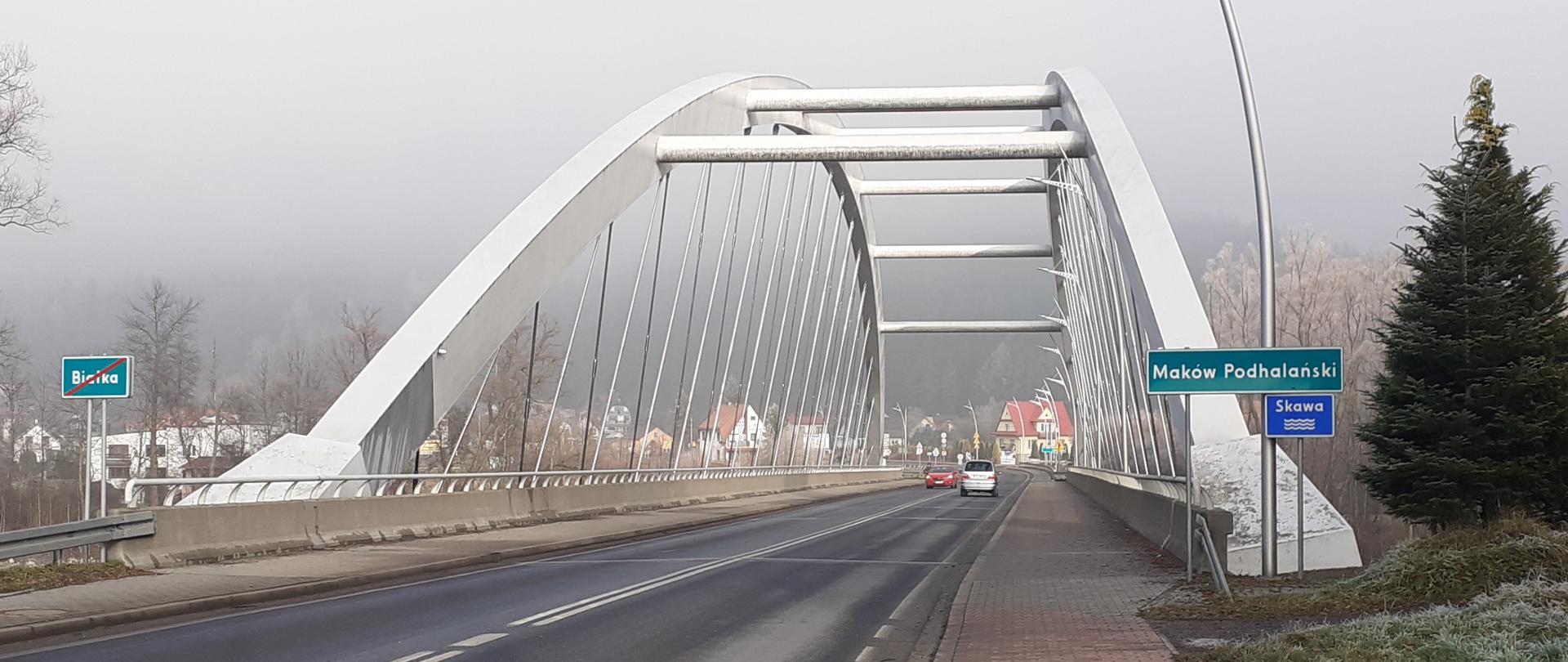 most w Makowie Podhalańskim, po prawej tabliczka z nazwą miasta, po moście jadą samochody