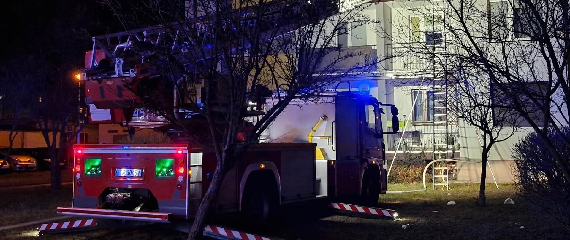 Na zdjęciu widoczny jest samochód specjalny z drabiną mechaniczną w trakcie prowadzonych działań. Drabina wysunięta jest i dostawiona do balkonu mieszkania w którym doszło do pożaru.