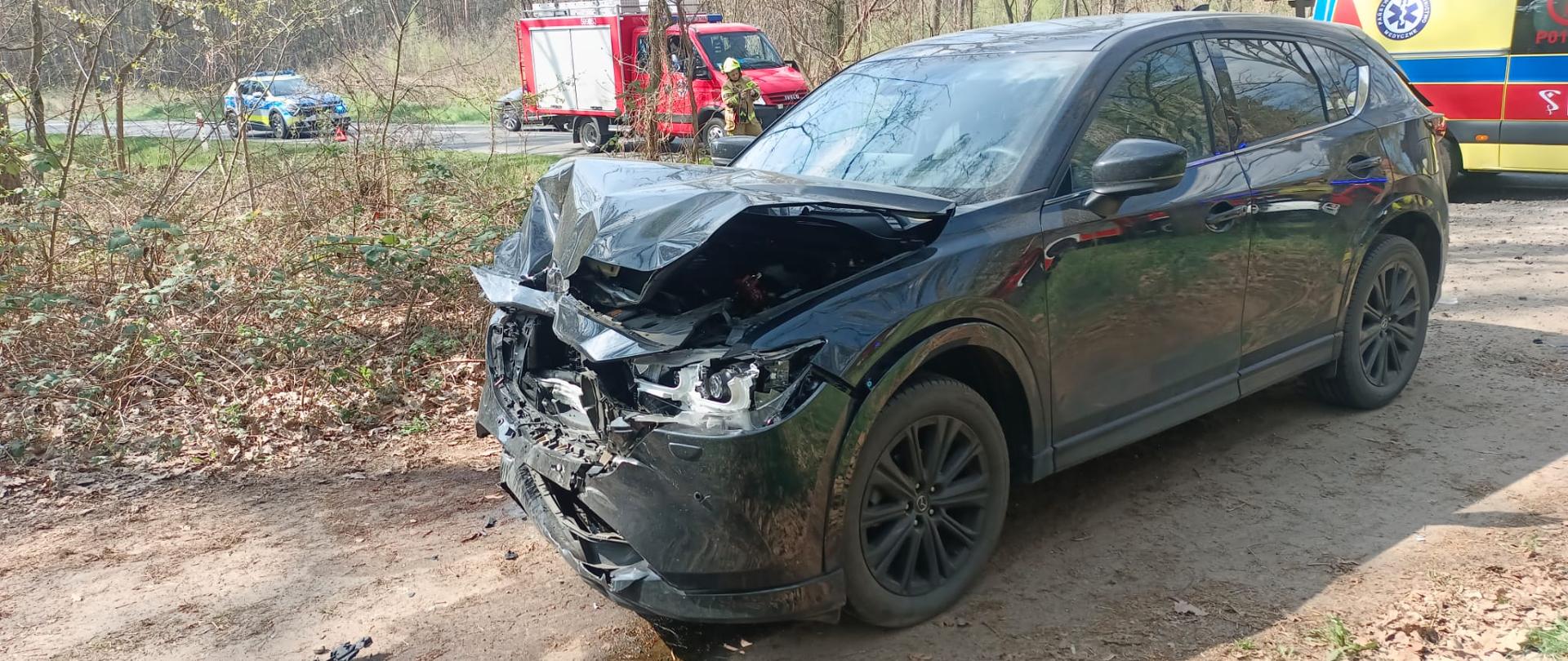 Pojazd ma mocno uszkodzony przód, jest na drodze leśnej