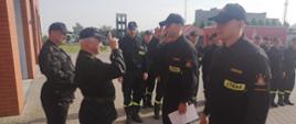 Funkcjonariusze podczas zmiany służby w obecności Komendanta i Dowódcy JRG. Dwoje z nich ma wręczane decyzje i oddają honor przełożonemu.