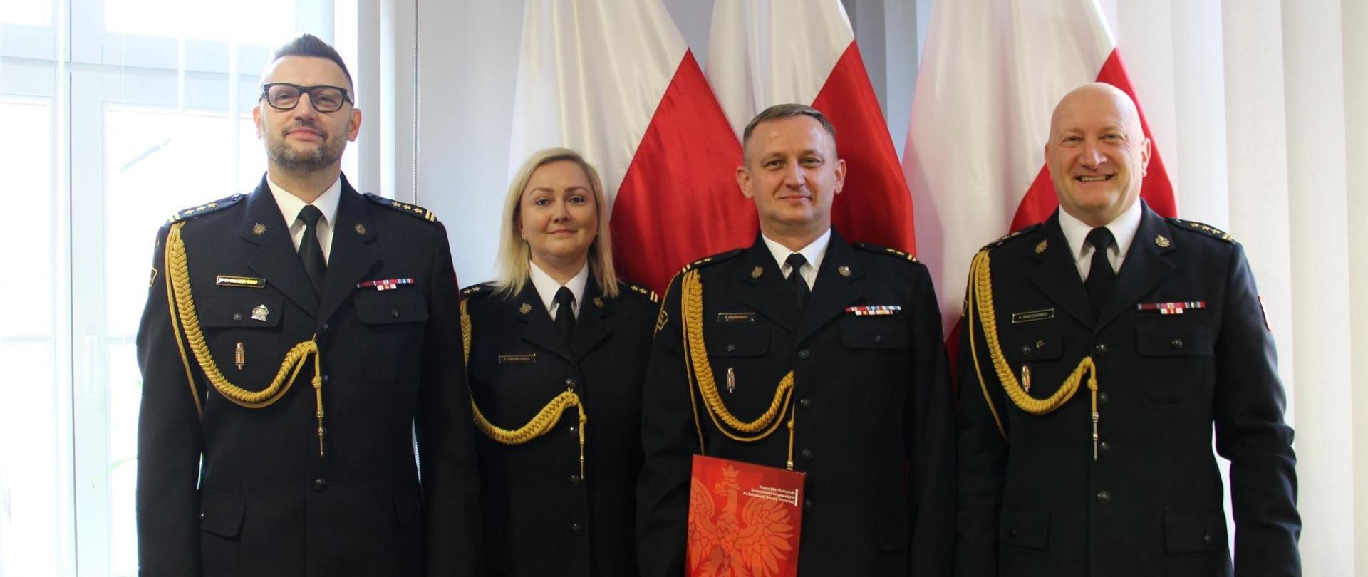 W gabinecie Kujawsko-Pomorskiego Komendanta Wojewódzkiego Państwowej Straży Pożarnej pozują do zdjęcia uczestnicy spotkania.