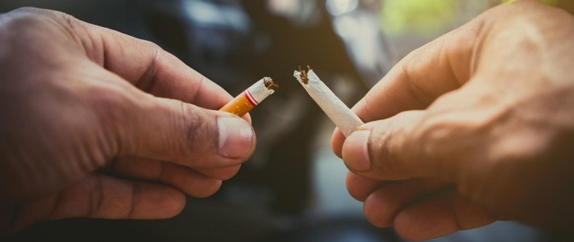 Dwie dłonie trzymające papierosy na różnorodnym tle