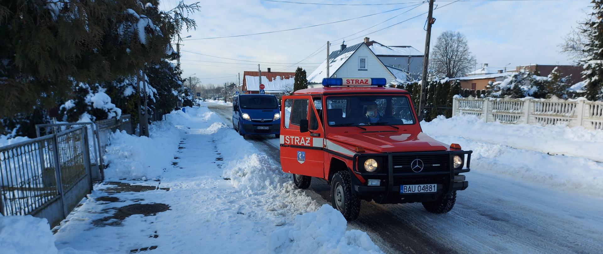 Na zdjęciu widoczne są 2 wozy pożarnicze uczestniczące w akcji dowożenia ludzi do punktów szczepień.
