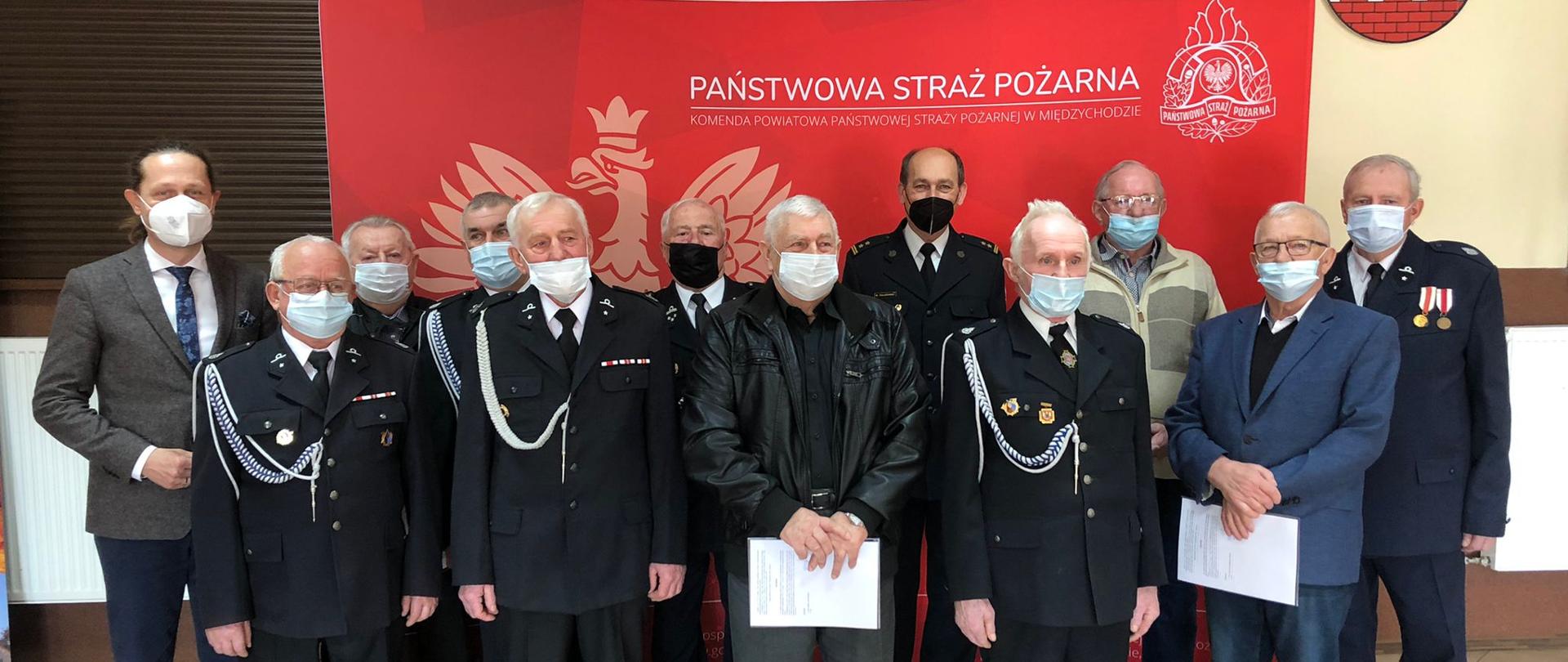 Na zdjęciu widać Komendanta Powiatowego, Starostę oraz druhów OSP na tle baneru Komendy Powiatowej PSP w Międzychodzie podczas robienia pamiątkowego zdjęcia