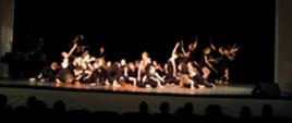 Zdjęcie grupy tancerek na scenie w ruchu. Zdjęcie na czarnym tle w oświetleniu strefowym.