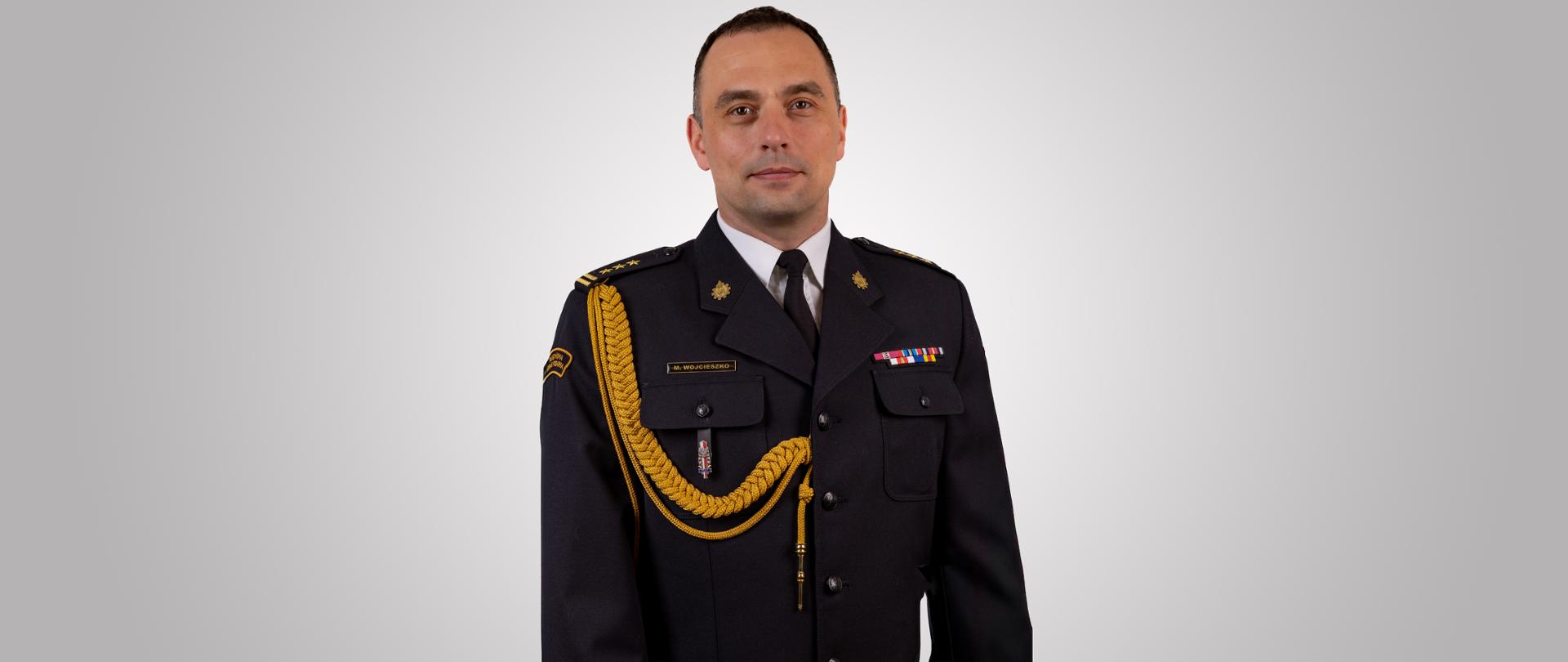 zdjęcie przedstawia starszego brygadiera Mariusza Wojcieszko Zastępcę Łódzkiego Komendanta Wojewódzkiego PSP w mundurze wyjściowym. Zdjęcie portretowe.