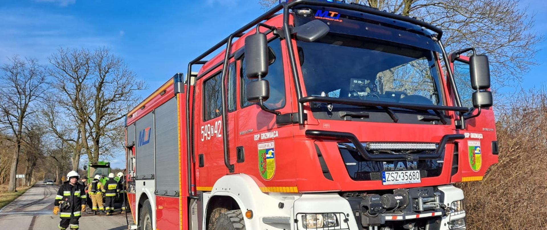 Na drodze asfaltowej w miejscowości Wielawino stoi zielona ładowarka, a przy niej strażacy, którzy ugasili pożar komory i instalacji elektrycznej. Strażacy ubrania w ubrania specjalne