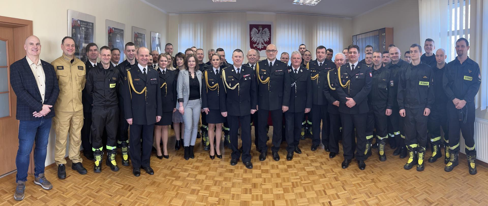 Zdjęcie grupowe pracowników i funkcjonariuszy KM PSP w Koszalinie na sali KM PSP Koszalin
