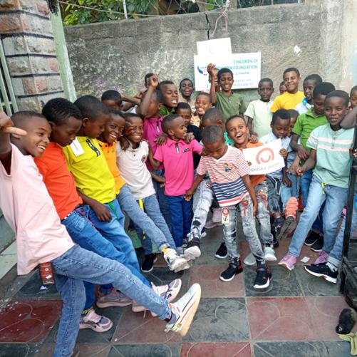 Czarnoskórzy chłopcy pozujący z logiem polskiej pomocy.