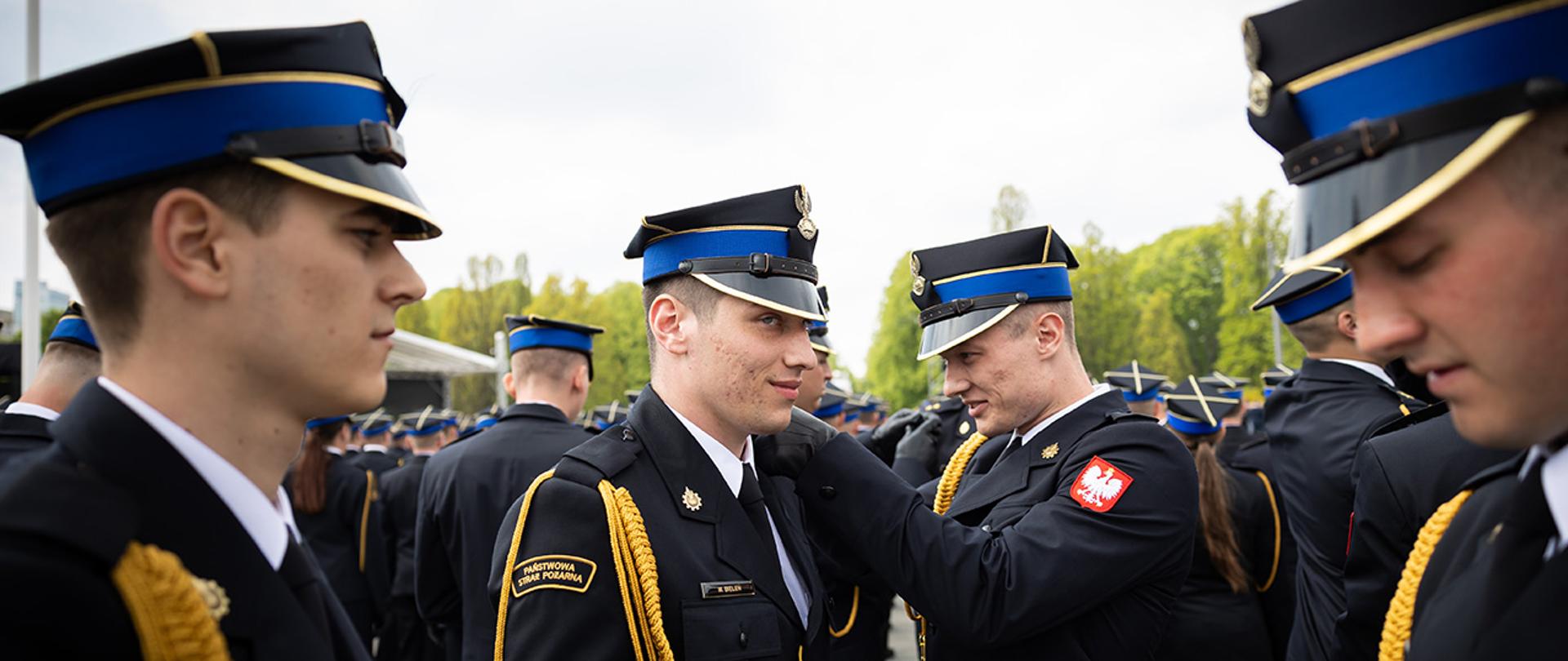 Strażacy nominowani na pierwszy stopień oficerski odwracają sobie pagony
