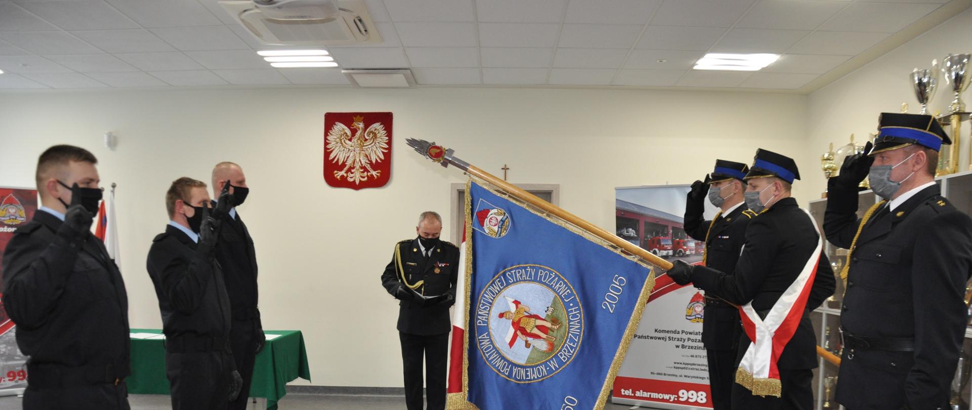 Na zdjęciu nowo przyjęci do służby strażacy składają rotę ślubowania. Od lewej: str. Łukasz Szczodrowski, str. Dariusz Meszka, str. Marcin Krawczyk. Po prawej poczet sztandarowy KP PSP. Po środku Komendant Powiatowy PSP w Brzezinach st. bryg. Dariusz Guzek
