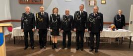 Druhowie oraz komendant miejski państwowej straży pożarnej stoją w świetlicy remizy 
