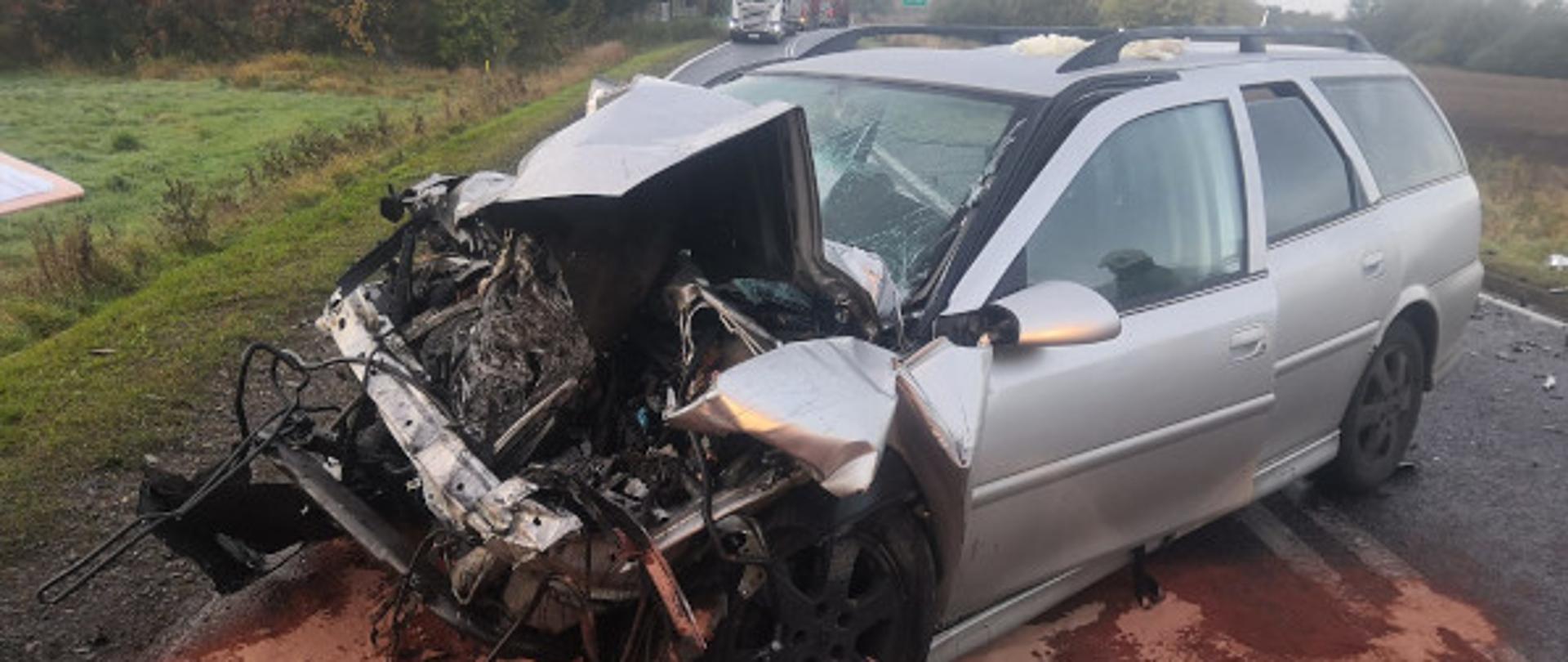 Na zdjęciu widać rozbity pojazd (uszkodzony cały przód), pojazd stoi w poprzek drogi krajowej nr 20. Uszkodzenie powstało na wskutek zderzenia z samochodem dostawczym.